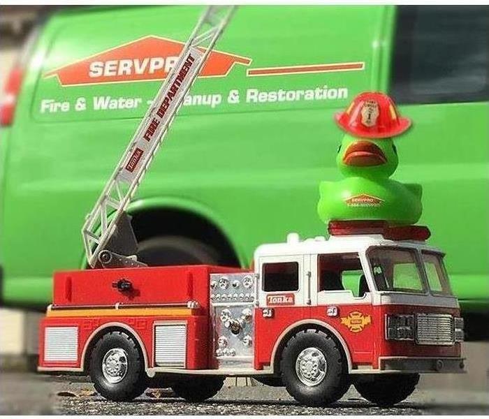 A toy duck on a toy firetruck. 